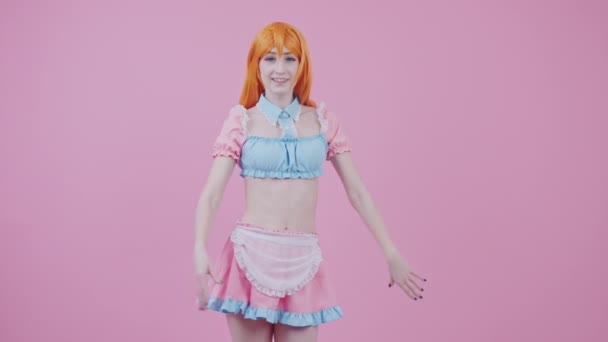 Caucasiano de cabelos vermelhos adolescente líder de torcida menina anima sua equipe médio longo estúdio tiro fundo rosa — Vídeo de Stock