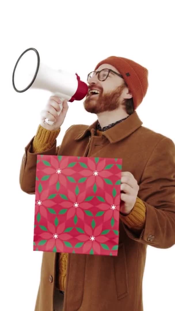 Jovem caucasiano barbudo homem atraente em um gorro gritando em megafone e segurando saco de compras isolado vertical no fundo branco — Vídeo de Stock