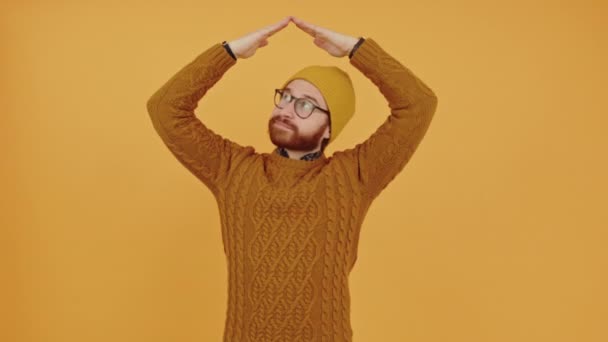Zamyšlený rozumný tisíciletý muž drží ruce nad korálky a rozhlíží se tím, že otáčí hlavu vlevo a vpravo střední studio záběr žluté pozadí — Stock video