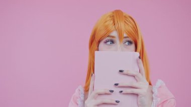 Şirin Shy Big-Eyed Kafkas Kız Pembe Defter 'in arkasına saklanıyor yakın plan pembe arka plan