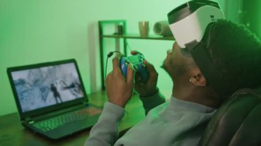 Siyah adam bilgisayarda VR kulaklık ve oyun pedi kullanarak para ödüyor. 