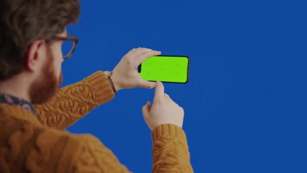 Καυκάσιος άντρας στα 30 του, να κυλάει και να αγγίζει το Smartphone του με την πράσινη οθόνη πάνω από την κάμερα ώμου. — Αρχείο Βίντεο
