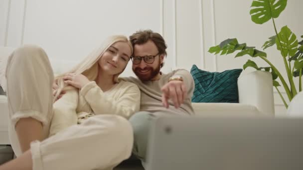 Duas pessoas caucasianas em um relacionamento sentado no chão, olhando para a tela de seu laptop — Vídeo de Stock