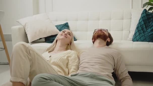 คู่รักผิวขาวฉลองวันผู้หญิง นอนอยู่บนพื้น มองขึ้นและยิ้ม — วีดีโอสต็อก