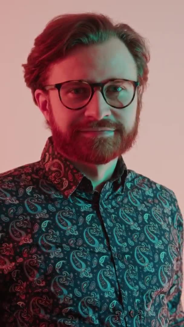 Plan vertical sympathique caucasien hipster homme hochant la tête et regardant la caméra avec un délicat sourire plan studio — Video