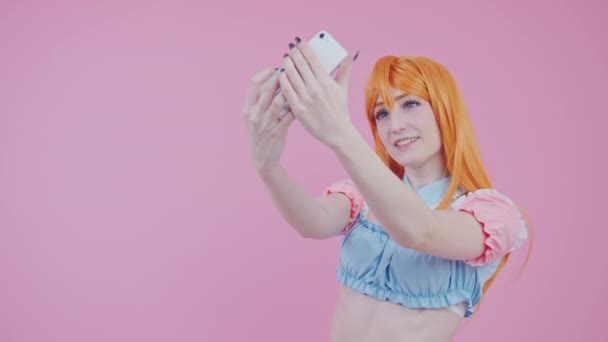 Beginner Caucasian Female Cosplayer Takes Photo Of Herself In A New Ginger Wig medium studio shot pink background — Stock Video