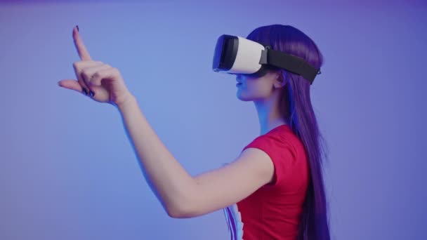 Beyaz kadın 20 'li yaşlarda, VR kullanıyor ve sol işaret parmağıyla orta ölçekli stüdyo fotoğrafıyla havayı değiştiriyor. — Stok video