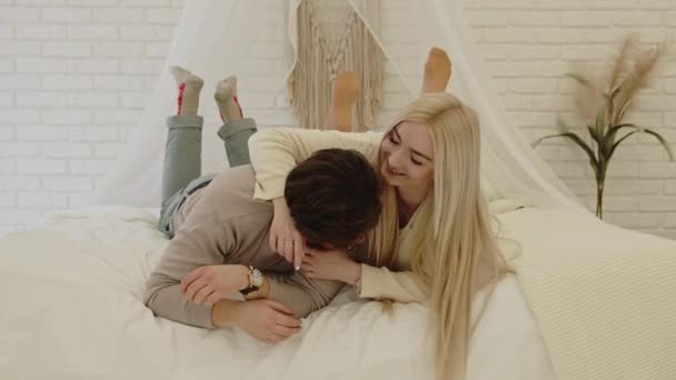 Ung entreprenör och hans vackra affärskvinna flickvän lägga sig på sin säng, leka med varandra — Stockvideo