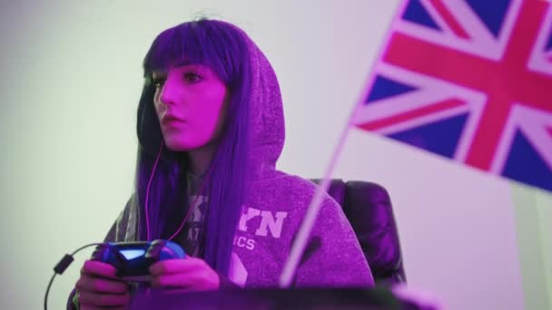 Hübsches kaukasisches Gamer-Mädchen mit Gamepad hinter der britischen Flagge Mittlere Nahaufnahme — Stockvideo