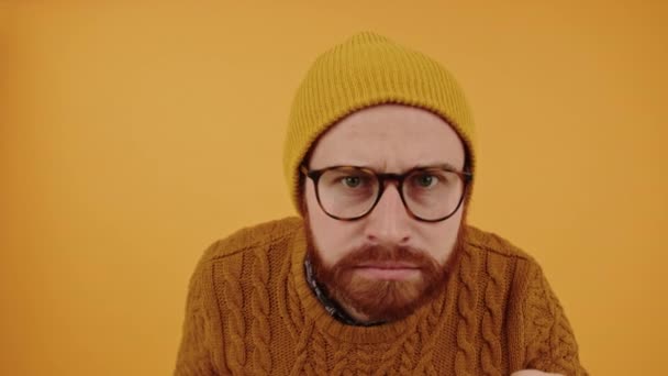 Middelbare leeftijd bebaarde hipster man kloppen op het scherm en verdacht kijken in, gele achtergrond studio schot — Stockvideo