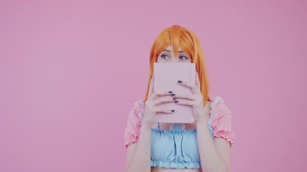 Kaukasische tiener leerling dragen schattig pastel top verbergen achter haar notebook medium studio schot roze achtergrond — Stockvideo
