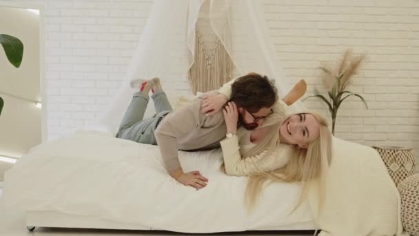 Ungdomlig gift par bindning och retas på sängen i sin helt nya lägenhet — Stockvideo