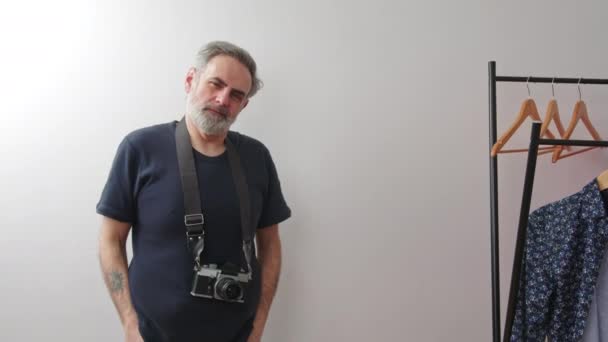 Hipster fotógrafo de mediana edad en sus 40 años posando con la cámara de cine por la pared blanca — Vídeos de Stock