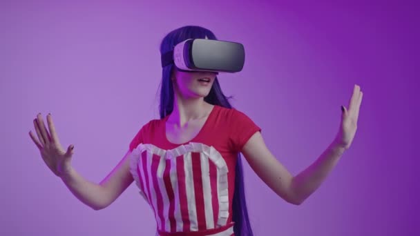 Uzun saçlı beyaz kız VR teknolojisi karşısında şaşkına döndü. Stüdyoda güçlü bir jestle mor arka plan çekti. — Stok video