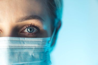 Portre fotoğrafını kapat. Genç bayan doktorun gözü. Hijyenik yüz cerrahi maskesi takarak bulaşıcı hastalıklara karşı koruma.