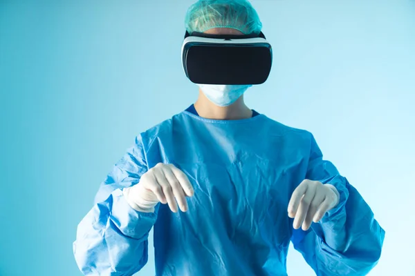 Médico caucásico utilizando el desarrollo tecnológico, gafas de realidad virtual. Tiro de estudio medio, fondo azul. — Foto de Stock