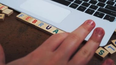 Bilgisayar masasındaki ahşap harf karolarından yaratılan Şubat ayının adı