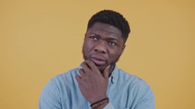 Genç Afrikalı Amerikalı zor bir karar veriyor yatay video portresi izole edilmiş sarı arka plan fotokopi stüdyosu