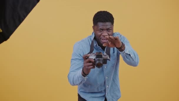 スタジオでの仕事でハンサムなアフリカ系アメリカ人の写真家水平ビデオ黄色の背景コピースペース — ストック動画