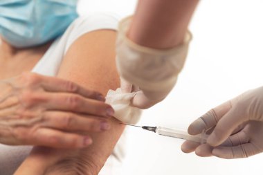 Yüz maskesi takan yaşlı bir kadın aşı oluyor. Coronavirus önleme ve tedavi kavramı.