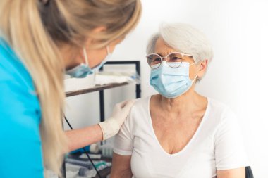 Genç hemşire, çoğunlukla kontrol sırasında yaşlı büyükanneyi neşelendiriyor. Güvenli ve sağlıklı bir emeklilik..