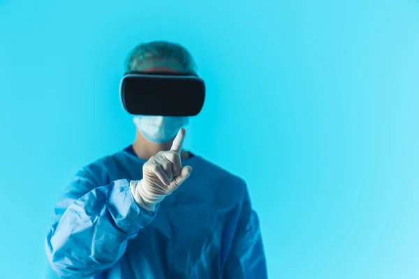 Professionele arts met virtual reality bril focus op de voorgrond vinger, geïsoleerde studio shot met blauwe achtergrond. — Stockfoto