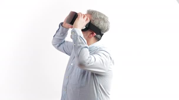 Около 50-летнего мужчины, оглядывающегося вокруг, пока у него есть vr goggles на белом фоне — стоковое видео