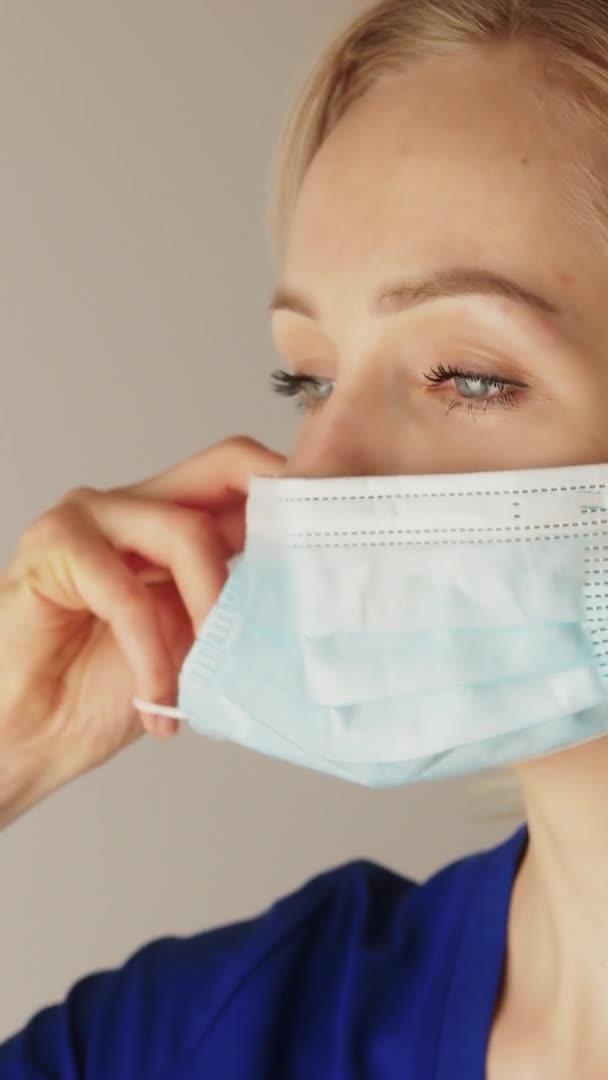 Vídeo vertical. Joven cirujana caucásica pensativa poniéndose o quitándose la mascarilla. — Vídeo de stock