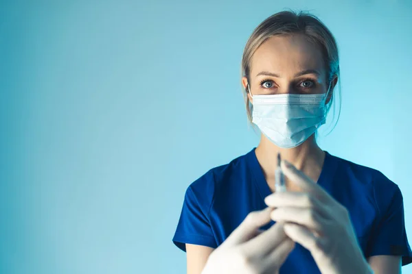 Jovem médica caucasiana preparando injeção de antibiótico. Médio close-up estúdio tiro fundo azul. — Fotografia de Stock