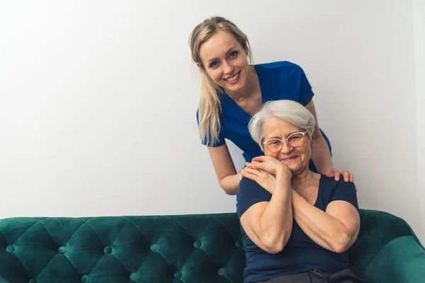 En äldre europeisk kvinna i en soffa som håller vårdnadshavarna i handen. Förhållandet mellan patient och läkare. — Stockfoto