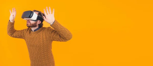 Portret van de jonge blanke man met behulp van virtual reality bril en het houden van handen omhoog vr reality concept kopieer ruimte oranje achtergrond geïsoleerd — Stockfoto