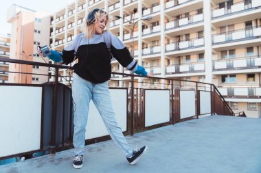 Kafkasyalı 90 'ların kızı, elinde klasik bir ses oynatıcısı tutarken dans ediyor. Mutlu ergenlik konsepti.