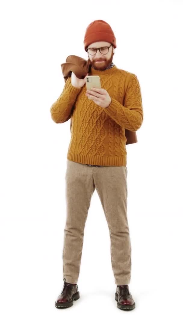 Vertikal video ung vit man tittar på sin telefon och skrattar vit bakgrund isolerad full skott — Stockvideo