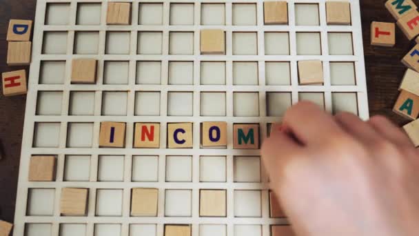 Vocabulary game a word INCOME made of wooden blocks by European player — Stock Video