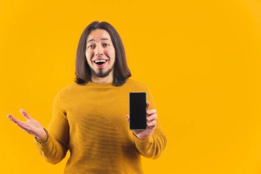 Beyaz sakallı adam elinde sahte siyah ekran akıllı telefon olan büyük satışlara şaşırdı ve hayrete düştü. Stüdyo çekimi sarı arkaplanda.