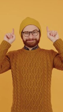 Dikey video Avrupalı hipster ellerini yukarıda tutuyor, portre üzerindeki noktalar izole edilmiş kopya alanı sarı arkaplan izole stüdyo görüntüleri 