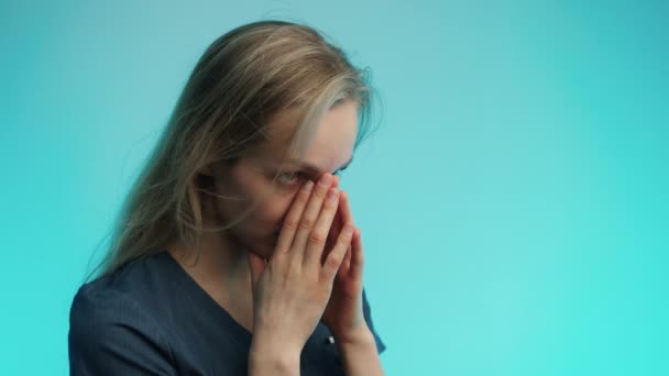 三十多岁的白内障外科医生用蓝色背景的两个手掌盖住她的脸。工作室拍摄. — 图库视频影像
