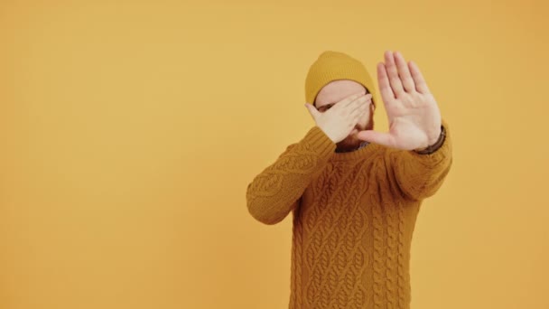 Молодой кавказский мужчина показывает лицевой платок, еще одна ладонь к камере изолированной студии снято желтым фоном копировальное пространство — стоковое видео