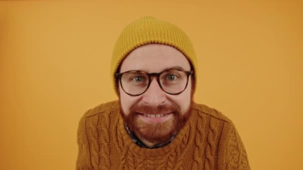 Fiatal jóképű szakállas fehér férfi néz a kamerába, mosolyog és rázza a fejét elszigetelt szelektív fókusz sárga háttér stúdió lövés másolás hely — Stock videók