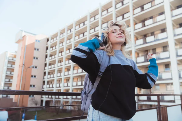 Glada kaukasiska tonåring tillbringa tid utomhus, dansa och lyssna på musik på sin gammaldags vintage spelare. Block av lägenheter i bakgrunden. — Stockfoto