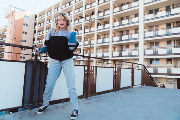 90-talets vibbar. Full utomhus bild av unga hipster flicka dans medan hon bär sina hörlurar och hålla gammaldags kassettspelare. — Stockfoto