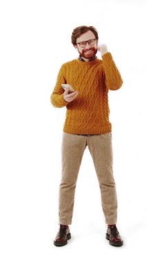 Tam kare Kafkasyalı genç adam telefonunu tutuyor, zafer gösteriyor, başarılı jest dikey video beyaz arka plan izole edilmiş. 