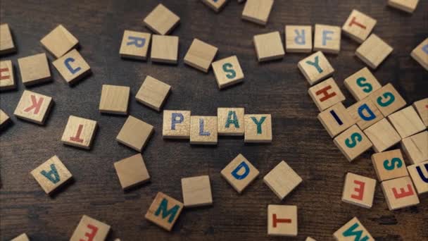 Vergrößern Sie das Wort PLAY aus verstreuten Buchstaben des Holzbuchstabens auf dem braunen Holztisch — Stockvideo