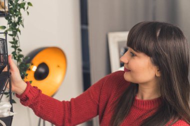 Kafkas esmer, bitkileri ve kişisel eşyaları rafa diziyor ve yeni evini dekore ediyor. Bireylik. 