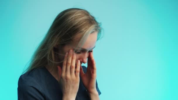 Sad exhausted caucasian woman touching her face over blue background. Studio shot. — Stock Video