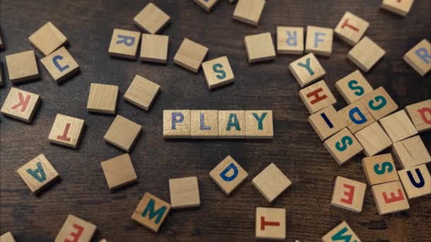 Zoom en la palabra PLAY hecho de bloques de madera alineados con letras de alfabeto en la mesa de madera marrón — Vídeos de Stock