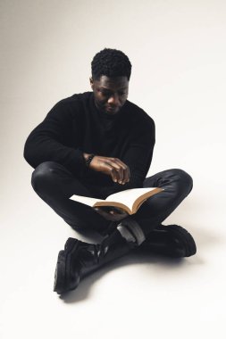 Beyaz arka planda oturan bir adam kitap okuyor - tam çekim 