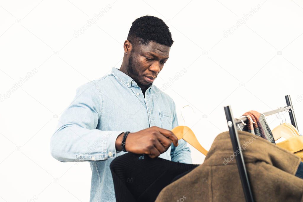 black man looking deciding clothe rack white background - waist up shot