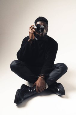 Afroamerikan fotoğraf makinesi ile beyaz arka planda oturuyor - tam çekim