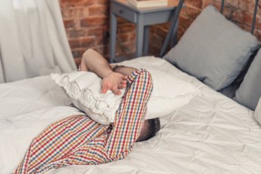 Hayal kırıklığına uğramış orta yaşlı işsiz bir adam ağlıyor ve yüzünü beyaz yastıkla örtüyor.